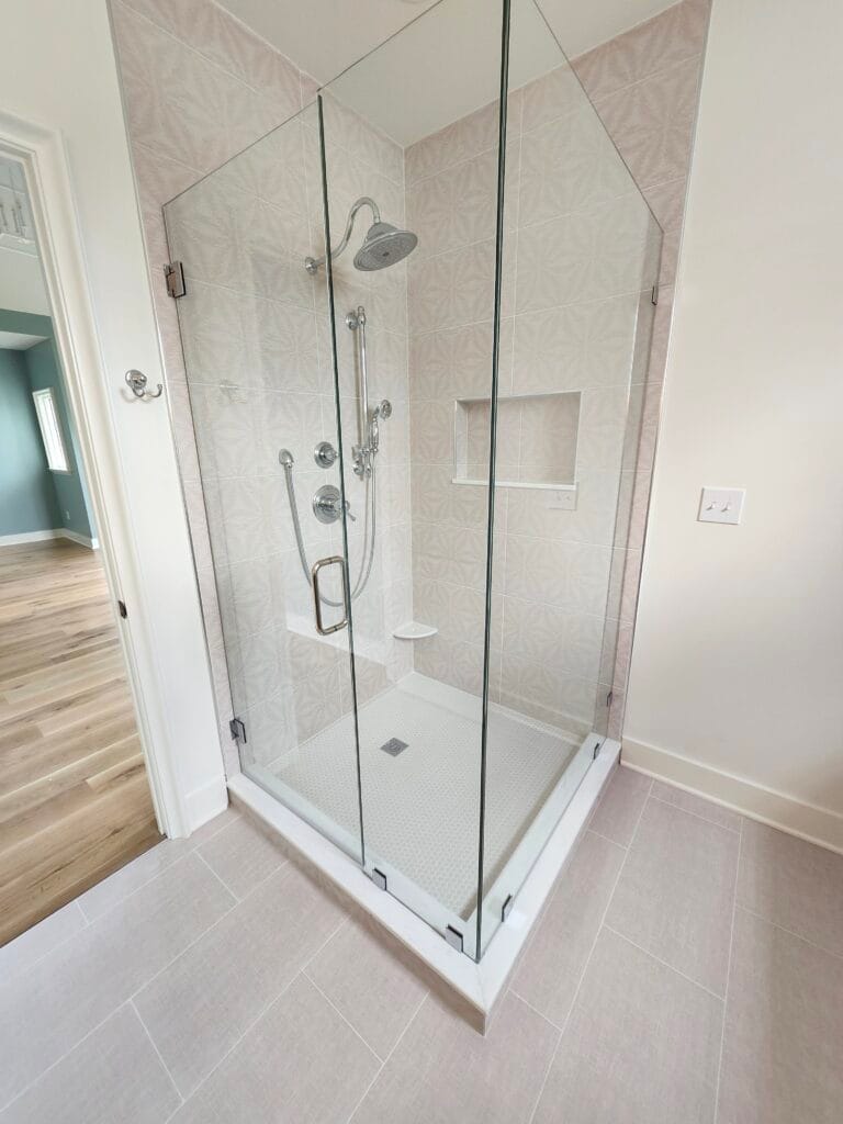 Frameless corner walk in shower with dual showerheads, built-in wall niches, and clean modern tile